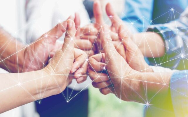 A team of people gives a thumbs-up, symbolizing agreement or success, overlaid with digital network graphics to suggest connectivity and teamwork in a modern, technological context focusing on stress management.